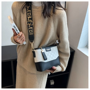 Detail of checkered crossbody bag with wide canvas strap and tassel on a female model