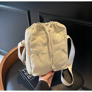 Dettaglio borsa a secchiello in nylon beige con texture stropicciata e tasca frontale
