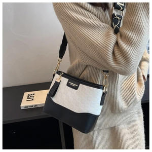 Detail of contrast bucket bag featuring embossed white panels and chic tassel charm