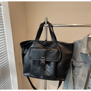 Détail du sac cabas noir avec boucle métallique et bandoulières réglables sur un cintre