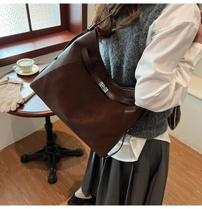 Detail of a large vintage brown shoulder bag with a metal twist lock and leather strap