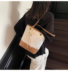 Close-up of dual-tone bucket bag with star embossing and pink tassel charm detail