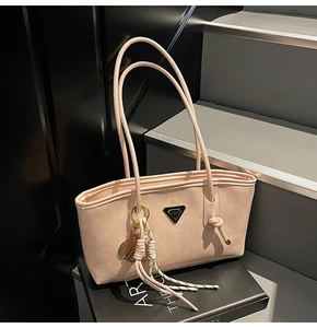 Détail d'un sac cabas rose avec plaque métallique triangulaire et pendentif raquette de tennis