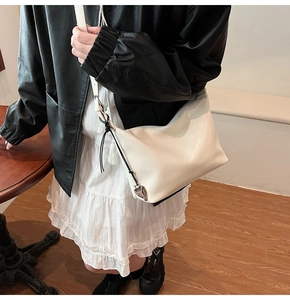 Détail du sac cabas crème avec pendentif cœur argenté et nœud en cordelette tressée