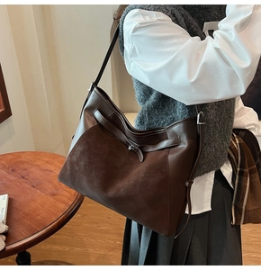 Close-up of vintage dark brown tote bag with adjustable strap and metal buckle detail