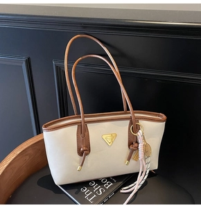 Détail du sac fourre-tout crème avec bordure marron et logo triangle doré chic