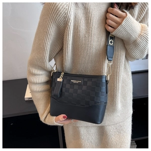 Detail of black crossbody bag with checkered embossing and fashion leather metal logo
