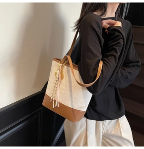 Close-up of star and floral embossed pattern on cream tote bag with brown leather strap