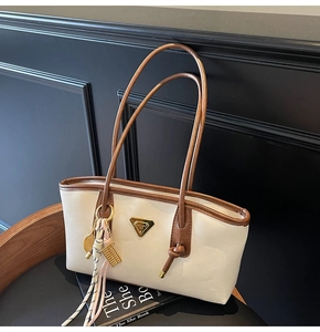 Détail du sac cabas crème avec logo triangulaire et pompon décoratif de tennis