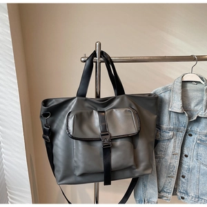 Détail du grand sac cabas gris avec poche à boucle suspendu à côté d'une veste en jean