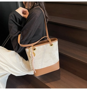 Detail of color-block tote bag with white textured pattern and brown leather straps