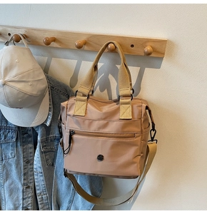 Detail of khaki nylon tote bag with reinforced handles and adjustable crossbody strap