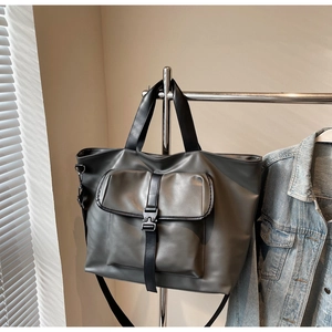 Détail d'un sac cabas gris avec poche avant fonctionnelle et sangle à boucle noire