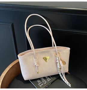 Détail du sac cabas rose clair avec plaque dorée triangulaire et nœud tressé