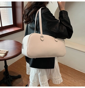 Close-up of cream-colored lychee textured leather tote bag on a model's shoulder