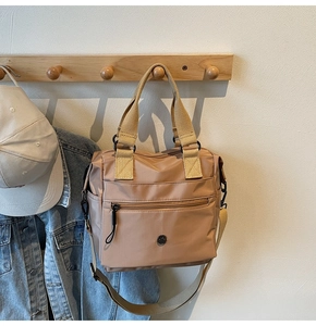 Detail of khaki nylon tote bag with front zipper pocket and adjustable shoulder strap