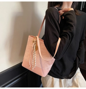 Pink underarm bucket bag with embossed star patterns and tennis racket charm detail