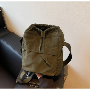 Dettaglio della borsa a secchiello in nylon verde oliva con coulisse su un libro nero