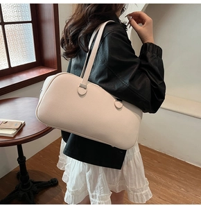 Detail of off-white lychee grain leather pillow bag with long handles in a lifestyle setting