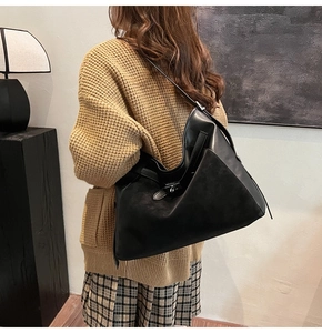 Detail view of black leather patchwork tote bag with silver buckle on a stylish model