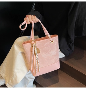 Detailed view of pink PU leather tote featuring embossed stars and braided tassels