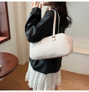 White pebbled leather shoulder bag shown on model with black jacket and white skirt