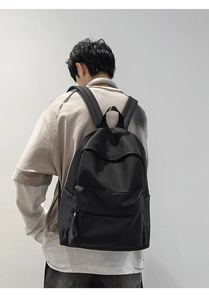 Minimalist black waterproof backpack on male model showing high-density nylon material and straps