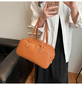 Chic orange-brown pebbled leather underarm bag shown with shoulder strap on a model