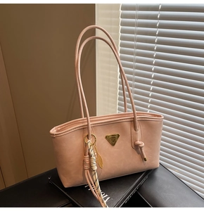 Détail du sac fourre-tout en similicuir rose clair avec logo doré et pendentif feuille