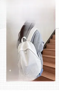 Close-up of white backpack with herringbone texture showing shoulder straps and zippers