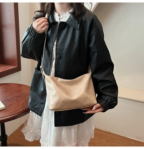 Détail du sac bandoulière en cuir crème avec des plis doux porté par un mannequin