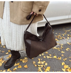 Detail of vintage brown tote bag with metal buckle and mixed leather textures