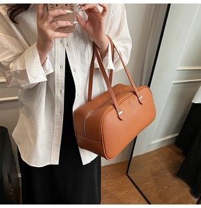 Litchi pattern leather tote bag in caramel brown worn over shoulder by a model