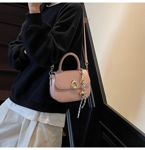 Detail of pink saddle bag featuring a gold arc lock and decorative geometric silk scarf