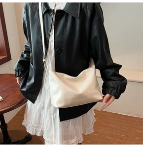 Sac hobo minimaliste en similicuir blanc crème porté avec une veste en cuir noir