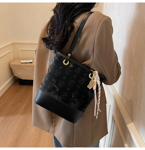 Close-up of black bucket bag with star embossing and golden architectural pendant
