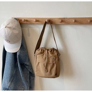 Vista dettagliata della borsa a tracolla kaki con coulisse appesa a un gancio in legno