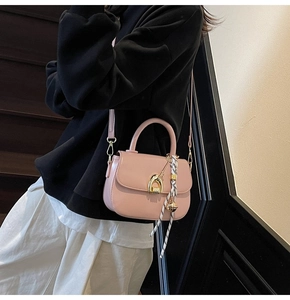 Close-up of pink saddle bag with gold buckle and decorative floral silk scarf handle