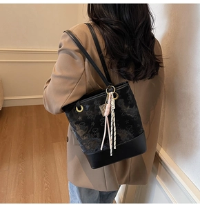 Detail of black bucket bag with star print, leather base, and dual-tone tassel accessory