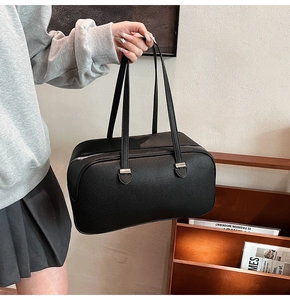Detail of black lychee-textured leather bowling bag with silver zipper and slim handles