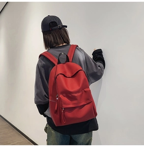 Detail of red water-resistant nylon backpack with front pocket and durable top handle
