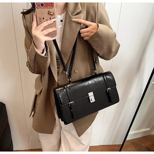 Close-up of black pleated leather crossbody bag featuring silver metal push-lock closure