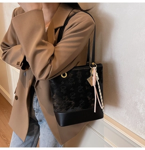 Detail view of black star-embossed bucket bag with a colorful woven tassel keychain