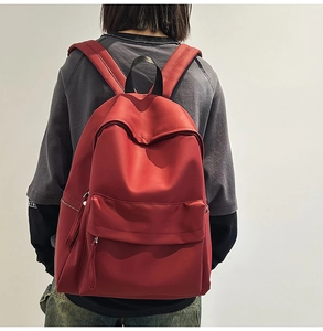 Rear view of a red nylon backpack on model showing durable straps and large main pocket