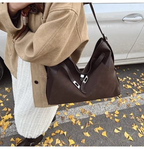 Detail of vintage brown shoulder bag with mixed texture stitching and silver buckle
