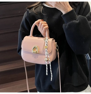 Close-up of pink saddle bag featuring a gold arched clasp and woven knot detail