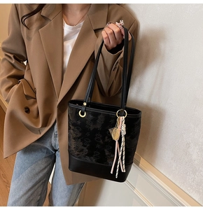 Detail of black jacquard tote bag with leather base and tennis racket charm accessory
