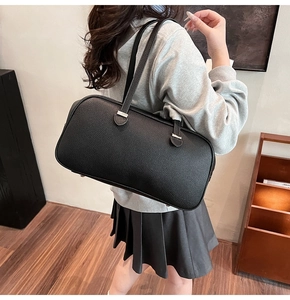 Model wearing a black lychee pattern leather shoulder bag in a minimalist indoor setting