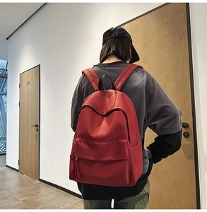 Rear view of a minimalist red large capacity backpack showing padded shoulder straps