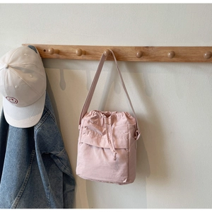 Dettaglio borsa a secchiello rosa con coulisse, tracolla e tasca frontale con patta